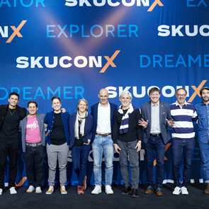 People posing infront of skucon 2024 stage backdrop
